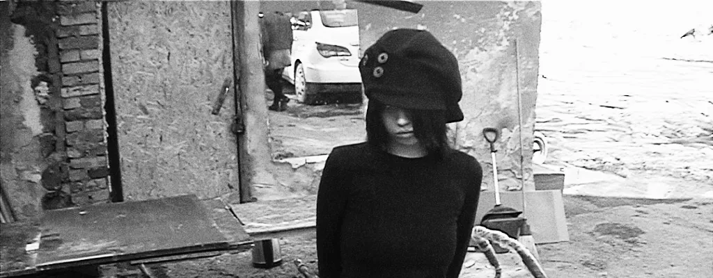 Model wearing the PETAL beret in a stark black and white scene