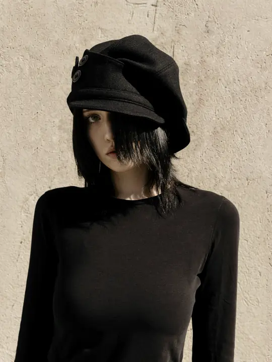 Model wearing the PETAL beret against a textured wall
