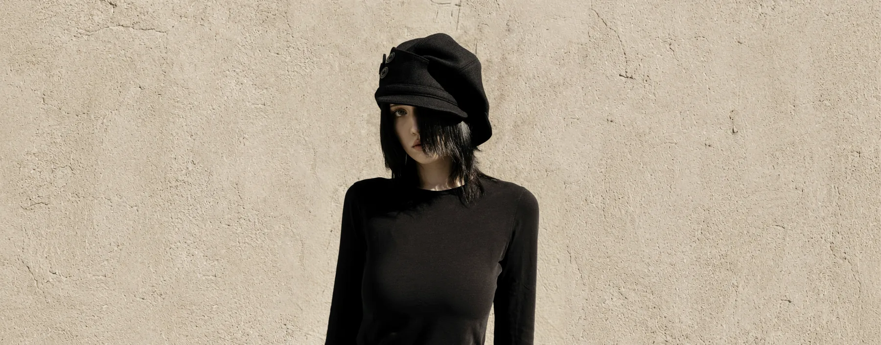 Model wearing the PETAL beret against a textured wall