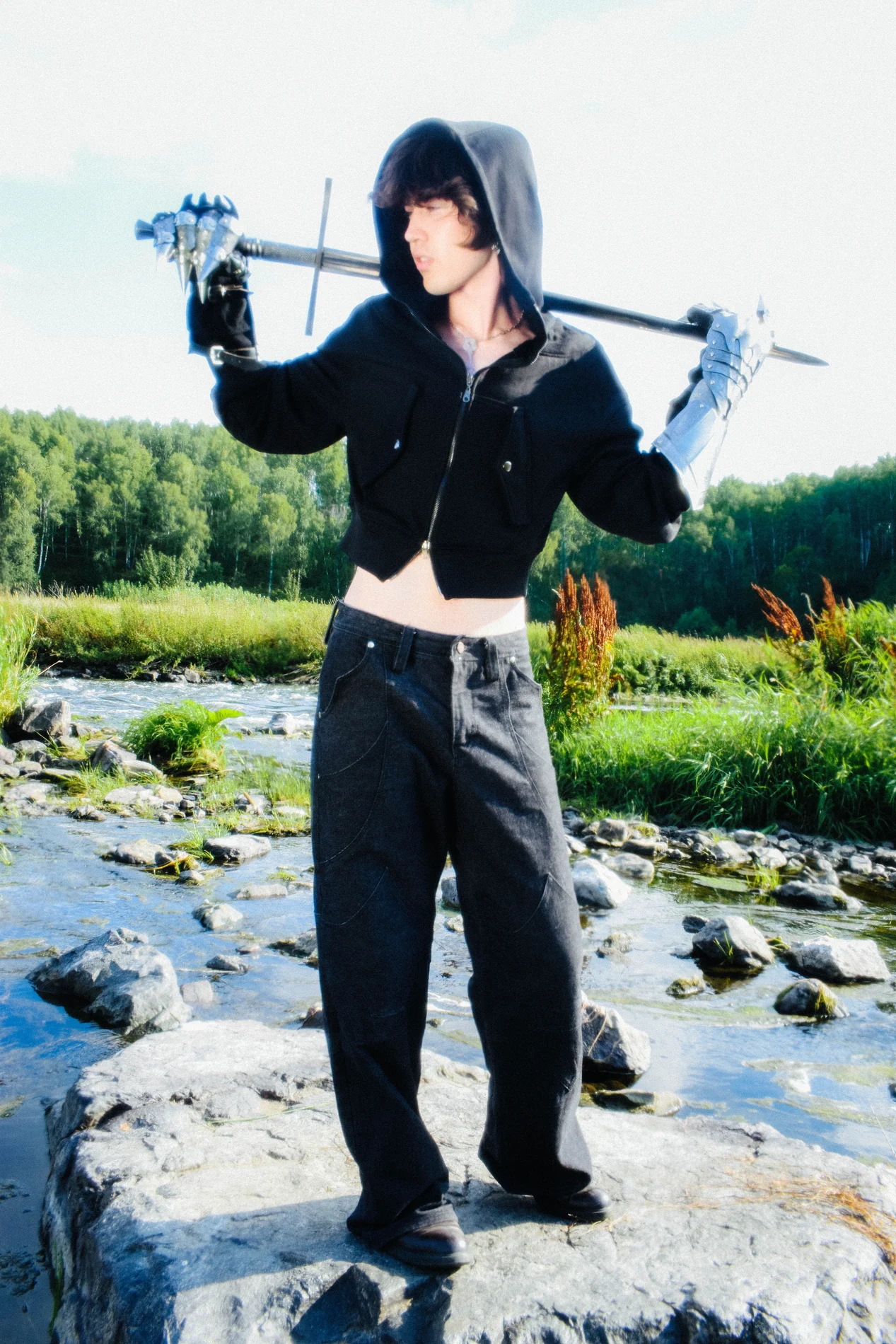 Model wearing the KEY hoodie by a river with chrome gloves